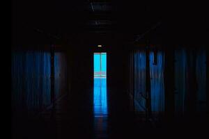 Blau Licht beim das Ende von ein dunkel Gang. Ende von dunkel Tunnel mit Magie Blau Licht. leeren dunkel Gang im Krankenhaus Labor. foto