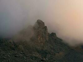 dramatisch Nebel unter Riese felsig Berge. gespenstisch atmosphärisch Aussicht zu groß Cliff im wolkig Himmel. niedrig Wolken und schön Rockies. minimalistisch Landschaft mysteriös Ort. foto