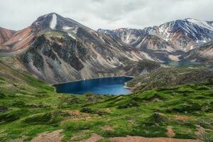 Blau Berg See im das Caldera. Berg Angebot gegen ein wolkig Himmel. Caldera von ein ausgestorben Vulkan ist umgeben durch ein Berg Bereich.Camping auf das Sommer- Grün Hohe Höhe Plateau. foto