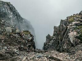 Berg Aussicht von Cliff beim hoch Höhe. mystisch Landschaft mit schön Scharf Felsen in der Nähe von Abgrund und Gänge im niedrig Wolken. schön Berg nebelig Landschaft auf Abgrund Kante mit Scharf Steine. foto