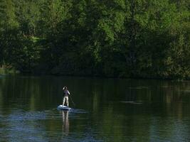 Frau Segeln auf schön Ruhe Grün Lagune. Sommer- Ferien Ferien Reise. sup Stand oben Paddel Tafel foto