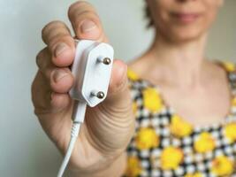 Frau Hand halten elektrisch Stecker. schließen hoch. Erde Stunde Speichern elektrisch Energie. foto