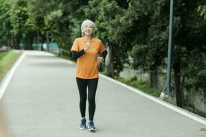 sportlich asiatisch Senior Frau Laufen draussen Joggen im Park. foto