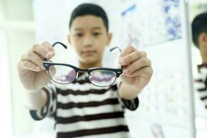 Clever jung Junge versuchen aus Neu Brille. foto