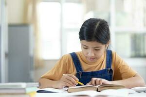 asiatisch Mädchen lesen und tun Hausaufgaben beim ihr Zuhause foto