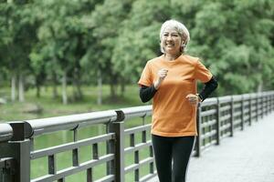 sportlich Senior Frau Laufen draussen Joggen im Park. foto