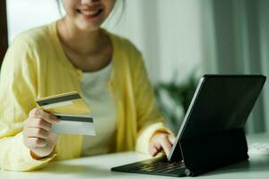 asiatisch Frau mit Laptop und Anerkennung Karte zum online Einkaufen. foto