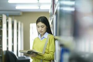 Schüler Stehen und lesen Buch beim Bibliothek. foto