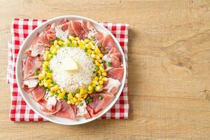 frisches Schweinefleisch roh in Scheiben geschnitten mit Reis und Mais auf dem Teller und bereit zum Kochen foto