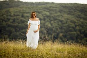 junge schwangere Frau auf dem Feld foto