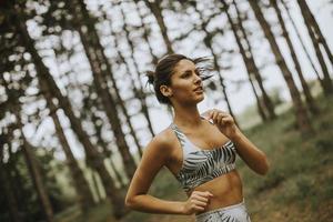 junge Fitnessfrau, die am Waldweg läuft foto