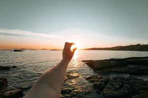 Hand, die die Sonne während eines Sonnenuntergangs ergreift foto