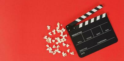 schwarze Klappe oder Filmtafel und Popcorn auf rotem Hintergrund. foto