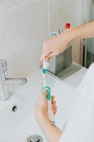 eine Frau, die seine elektrische Zahnbürste wäscht
