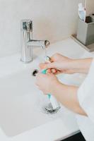 eine Frau, die seine elektrische Zahnbürste wäscht