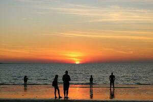 Menschen suchen beim ein Strand Sonnenuntergang foto