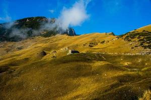 Hütte zwischen den gelben Herbstfeldern auf den Alpen