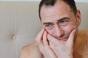 Mann, der mit Zahnschmerzen im Bett bleibt foto