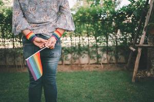 asiatische Dame, die Regenbogenfarbflaggensymbol des lgbt Stolzmonats hält, feiern jährlich im Juni soziales von schwulen lesbischen bisexuellen Transgender-Menschenrechten