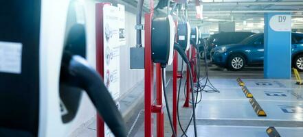 elektrisch Auto Laden Bahnhof zum aufladen ev Batterie. Stecker zum elektrisch Fahrzeug. ev Ladegerät. Laden Punkt beim Auto Parkplatz Menge von das Einkaufszentrum. sauber und nachhaltig Energie. kommerziell ev Laden Punkt. foto