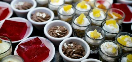 Dessert Buffet Gastronomie Konzept. selektiv Fokus Dessert auf Buffet Schalter. Dessert im Platte, Tasse, und Glas auf Tabelle beim Restaurant zum Mittagessen Büfett. Süss Lebensmittel. rot Gelee Agar, Schokolade Mousse. foto