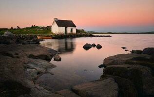 atemberaubend Sonnenaufgang Seeufer Landschaft von Fischers Hütte reflektiert im Wasser beim Geröll im connemara National Park ,Bezirk Galway ,Irland foto