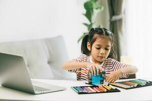 süß asiatisch wenig Mädchen mit Farbe Bleistifte und Laptop beim Zuhause foto