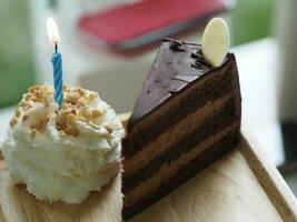 Geburtstag Kuchen Stück Schokolade Kuchen mit ausgepeitscht Sahne auf oben Mandel Kerze im hölzern Tablett foto