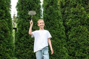 ein süß Junge ist halten ein Badminton Schläger im seine Hände, vorbereiten zu schlagen aus ein Federball foto