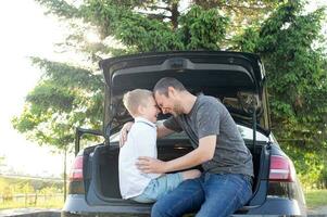 Vater mit Tochter Sitzung auf Auto Kofferraum nach Schulung foto