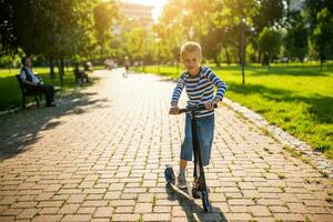 wenig Junge Reiten ein Roller im das Park foto