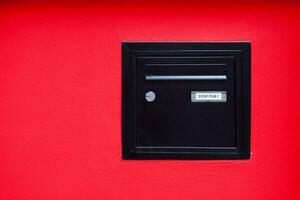 schwarz Briefkasten verkrustet im ein rot Mauer foto