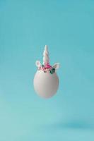 einzelnes weißes Ei mit Einhorndekoration kreativer minimaler Osterhintergrund mit Kopienraum foto
