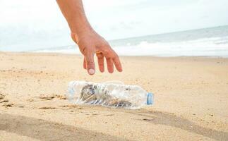 Hand pflücken oben Plastik Flasche Reinigung auf das Strand. speichern das Welt Konzept. Umfeld, Ökologie Pflege, verlängerbar Konzept, Natur Erhaltung Tourismus foto