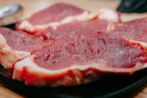 roh Rindfleisch Fleisch zum Steak Vorbereitung. roh Rindfleisch geschnitten, Vorbereitung von Fleisch zum Kochen Steak beim das kulinarisch Meister Klasse. roh Fleisch auf ein schwarz Platte. foto