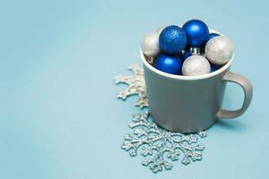 Blau und Silber Weihnachten Bälle im ein Tasse auf ein Blau Hintergrund. kreativ Konzept von Weihnachten und Neu Jahr. foto
