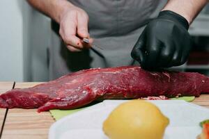 roh Rindfleisch Fleisch zum Steak Vorbereitung. roh Rindfleisch geschnitten, Vorbereitung von Fleisch zum Kochen Steak beim das kulinarisch Meister Klasse. roh Fleisch auf ein schwarz Platte. foto