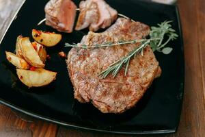 Rindfleisch Steaks auf ein schwarz Teller mit Grüns. foto