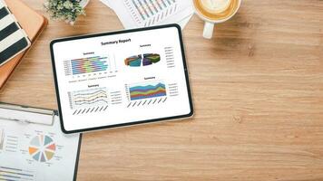 tablet mit diagrammen und berichten über den schreibtischarbeitsplatz. Draufsicht flach liegen foto