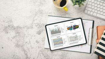 tablet mit diagrammen und berichten über den schreibtischarbeitsplatz. Draufsicht flach liegen foto