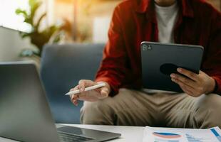 Geschäftsmann Sitzung Vorderseite Tablette ,Laptop Computer mit finanziell Grafiken und Statistiken auf monitor.at Büro foto