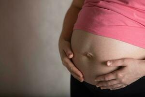 jung schwanger Frau berührt ihr Bauch. dramatisch Licht. foto