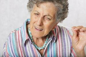 alt Frau ist Reinigung ihr Ohren mit Baumwolle Tupfer foto