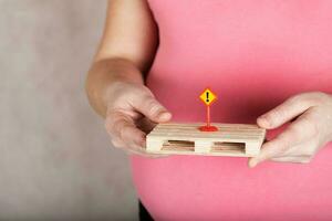jung schwanger Frau hält Zeichen Ausruf markieren. foto