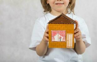 Junge von fünf Jahre ist behalten handgemacht Karton Papier Haus. foto