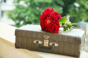 Jahrgang Koffer und ein Bündel von rot Rosen foto