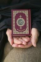 das Koran im das Hände von Senior Frau foto