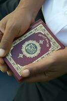 das Koran im das Hände von ein Mann foto