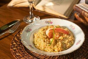 schön Gericht von Garnele Risotto mit Weiß Wein. im das Hintergrund alt Bücher foto