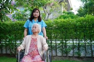 asiatische ältere Frau mit Behinderung, die im Park im Rollstuhl sitzt, medizinisches Konzept. foto